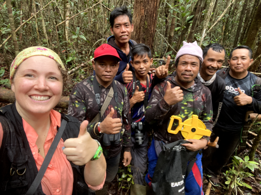 7 people taking a selfie. They are in the forest wearing hiking gear