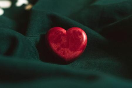 red heart over dark green fabric background